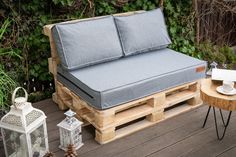 a couch made out of wooden pallets with black cushions and pillows on top of it