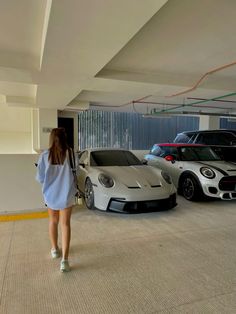 a woman is walking towards two cars in a parking garage with no one on it