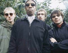 a group of young men standing next to each other in front of trees and bushes