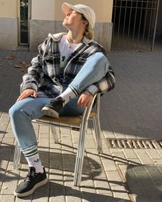 a woman sitting on top of a metal chair next to a brick walkway and building