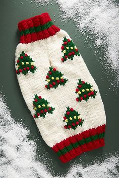 a knitted mitt with holly and berries on it sitting in the middle of snow