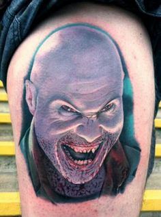 a close up of a person's leg with a tattoo on it and an evil face