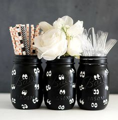 four black mason jars with white flowers in them and some paper straws sticking out of the lids