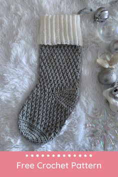 a knitted stocking laying on top of a white blanket next to christmas ornaments