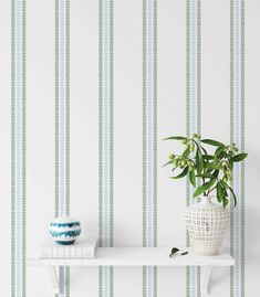 a potted plant sitting on top of a white shelf next to a wallpaper