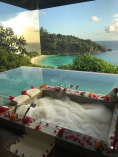 an outdoor jacuzzi with flowers and candles on the floor in front of water