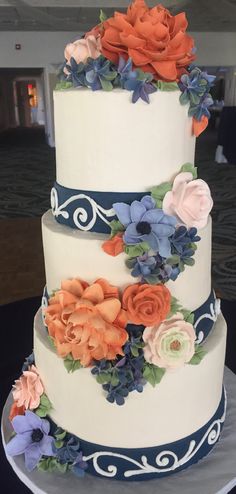 a three tiered wedding cake with flowers on the top and blue trimmings