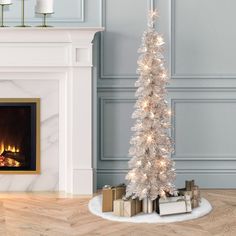 a white christmas tree in front of a fireplace