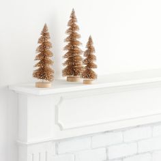 three small christmas trees sitting on top of a mantle