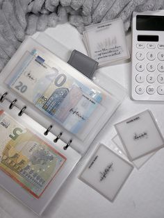 a calculator, money and other items on a white tablecloth with a cell phone