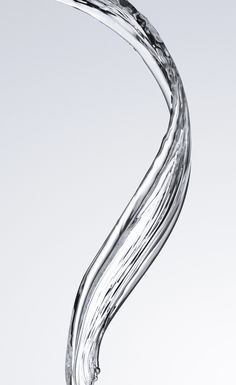 the water is flowing in to the glass with it's long, curved tail