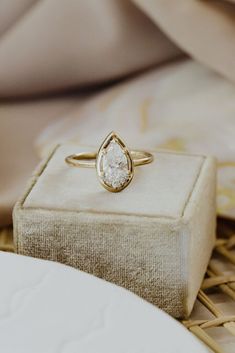 a diamond ring sitting on top of a cushioned box next to a white pillow