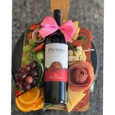 a bottle of wine sitting on top of a plate filled with cheeses and fruit