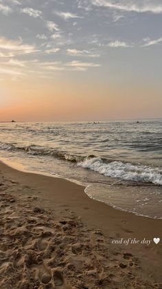 the sun is setting at the beach with footprints in the sand