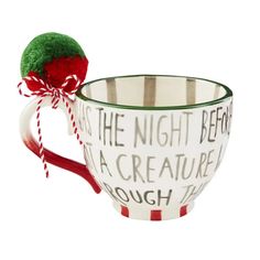 a coffee cup with a red and white striped handle is decorated with a christmas ornament