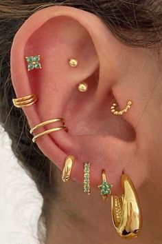 an ear with three different types of piercings on it's sides and one is gold