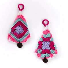 two small crocheted ornaments hanging from hooks on a white surface, one is pink and the other is blue