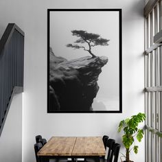 a black and white photo hanging on the wall next to a wooden table with chairs