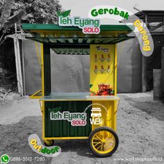 a yellow and green cart sitting on top of a dirt field