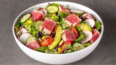 a white bowl filled with lots of different types of food on top of a table