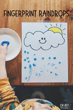 a child's hand is holding a paper plate with water and clouds on it