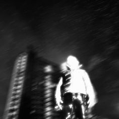 a man riding a snowboard down the side of a hill in front of tall buildings