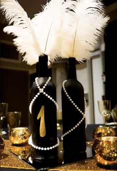 two black bottles with pearls and white feathers in them