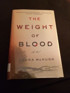 the weight of blood by laura mchugh on a black tablecloth with a red and white book cover