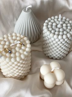 three white vases sitting on top of a bed next to each other with beads