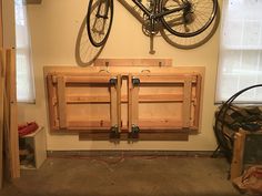 a bike mounted to the wall in a room with unfinished wood cabinets and tools on it