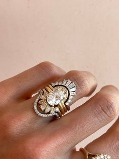 a woman's hand with two rings on it and an engagement ring in the middle