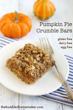 pumpkin pie crumble bars on a white plate with a fork and two small pumpkins in the background