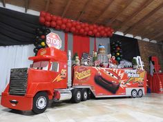 a large red truck parked in front of a wall with balloons on it's side