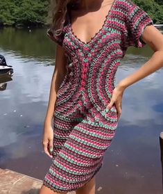 a woman in a short dress standing next to a body of water with her hands on her hips