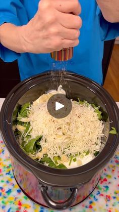 a person pouring grated cheese into a slow cooker