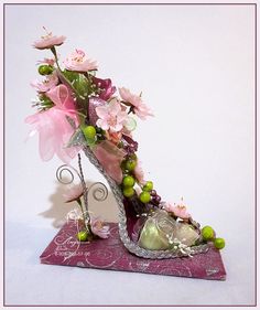 a vase filled with flowers on top of a pink table cloth next to a pair of shoes