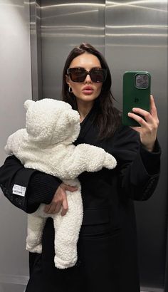 a woman taking a selfie while holding a white teddy bear in front of her