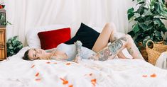 a woman laying on top of a bed next to a plant