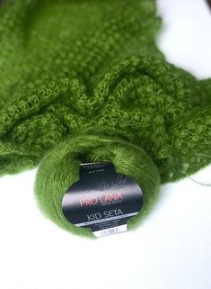 a green knitted blanket laying on top of a white table