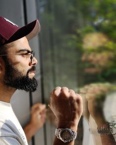 a man with a watch on his left hand looking out the window at another person