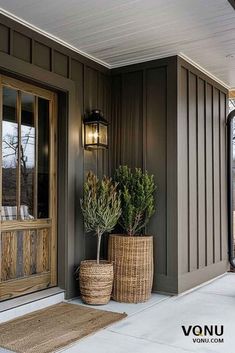 two planters on the front porch of a house with brown siding and wood trim