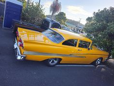 an old yellow car parked in a parking lot