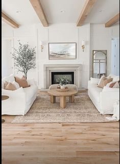 a living room filled with white couches and a coffee table in front of a fire place