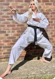 the woman is practicing karate in front of a brick wall with her hand on her hip