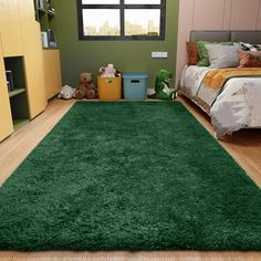 a green rug in a bedroom next to a bed and dresser with teddy bears on the floor