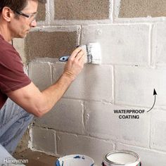 a man is painting a brick wall with white paint