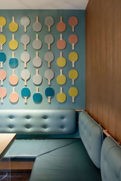 a room with blue couches and colorful art on the wall behind it, including ping pong paddles