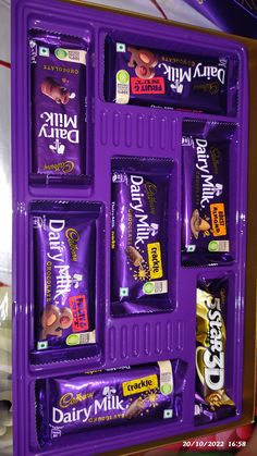 an assortment of dairy milk snacks displayed in a purple display case on a counter top