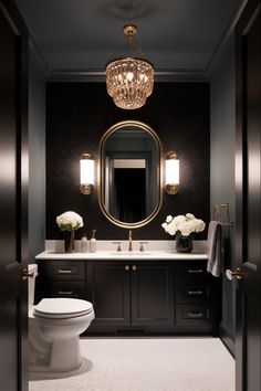 a white toilet sitting under a bathroom mirror next to a sink and a light fixture