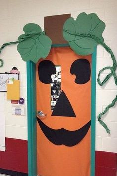 an orange door decorated with green leaves and a jack o'lantern on the front